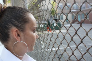 Sara Ferreira looks at the pplayground behind her house--the Oliver Street playground--where her son cannot go to school.