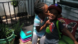 Lela Barrow, 6, kisses her little brother Richard, 3,  and helps him with his backpack. Because of "One Newark," they can't walk to school together with their grandmother